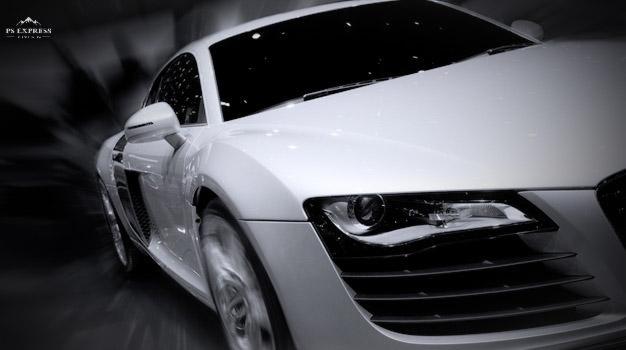 Dynamiczne ujęcie białego sportowego samochodu z rozmytym tłem, podkreślające jego aerodynamiczną sylwetkę i prędkość.