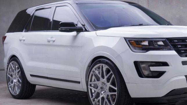 Biały SUV z przyciemnionymi szybami bocznymi i tylną, chromowanymi felgami, oraz czarnym dachem, zaparkowany na szarym tle.