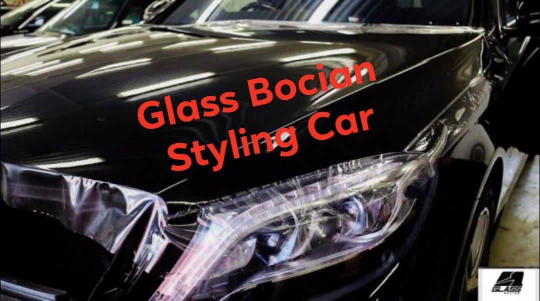 Czarny samochód z nałożoną folią ochronną na przedni reflektor, widoczne logo firmy na dole zdjęcia.