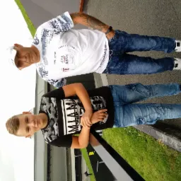 Portret ojca i syna w casualowych ubraniach na tle betonowej powierzchni i trawy, obaj patrzą w obiektyw.