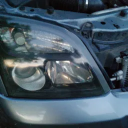 Reflektor samochodu po renowacji z widocznymi elementami silnika w tle.
