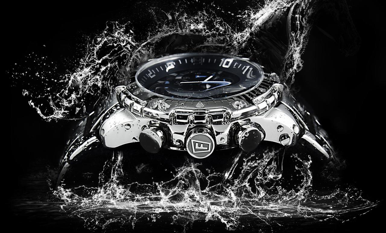 Chromowany męski zegarek z logo na czarnym tle, otoczony rozpryskującą się wodą, podkreślony kontrastowym oświetleniem.