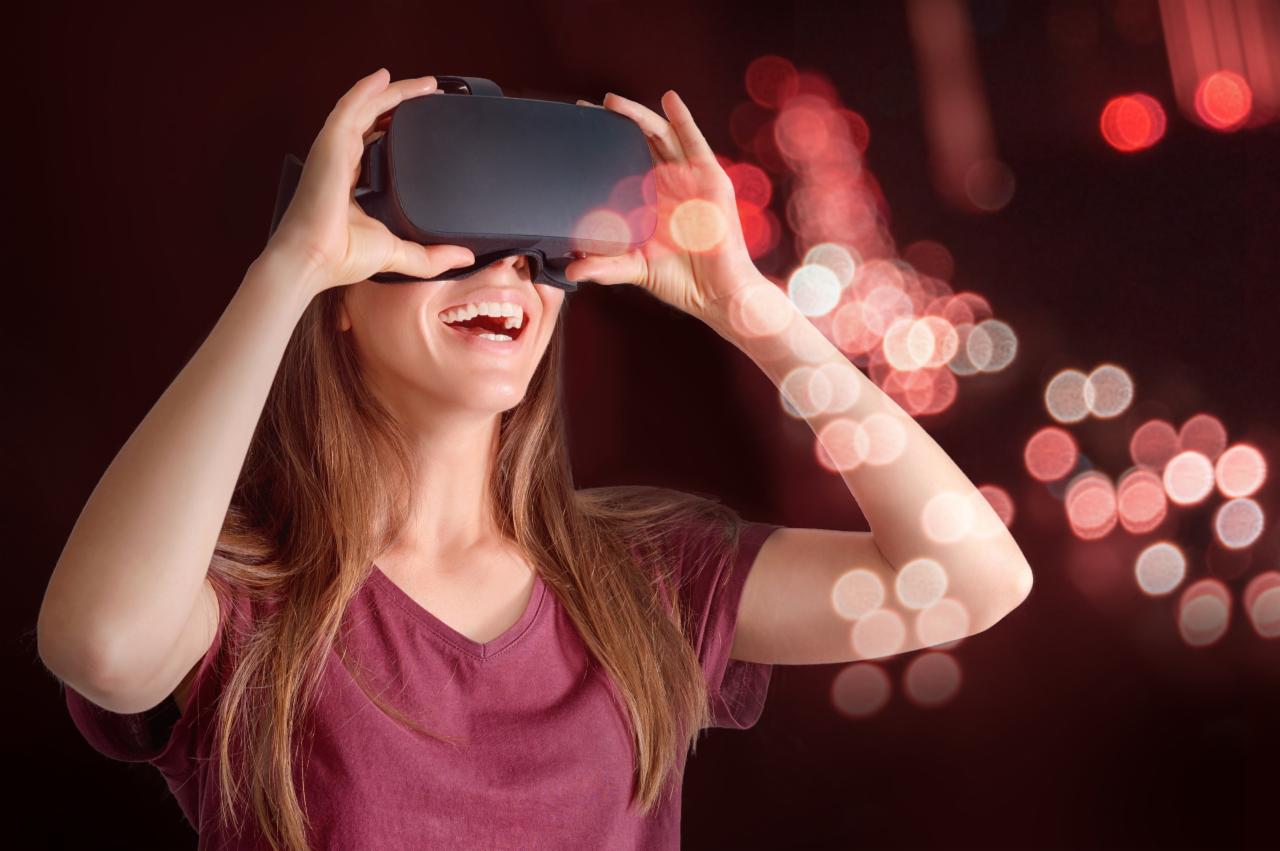 Uśmiechnięta kobieta z rozpuszczonymi włosami testuje zestaw do wirtualnej rzeczywistości na tle czerwonych świateł bokeh.