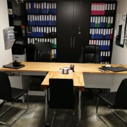 Kreatywna Księgowość sp. z o.o - Biuro w Radomiu z drewnianym biurkiem, czarnymi krzesłami i regałami wypełnionymi segregatorami.