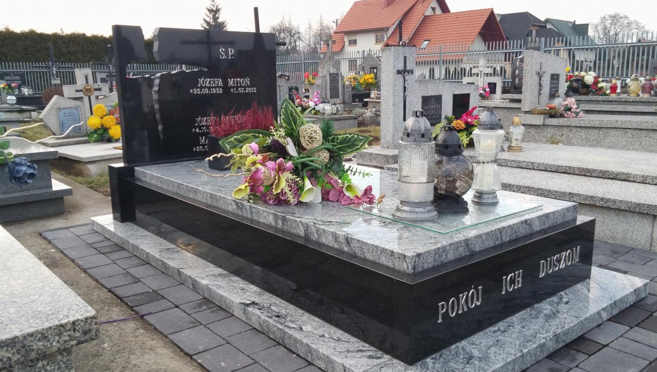 Granitowy nagrobek z inskrypcją 'Pokój ich dusz' oraz kompozycją kwiatową i lampionami na cmentarzu w Bochni.