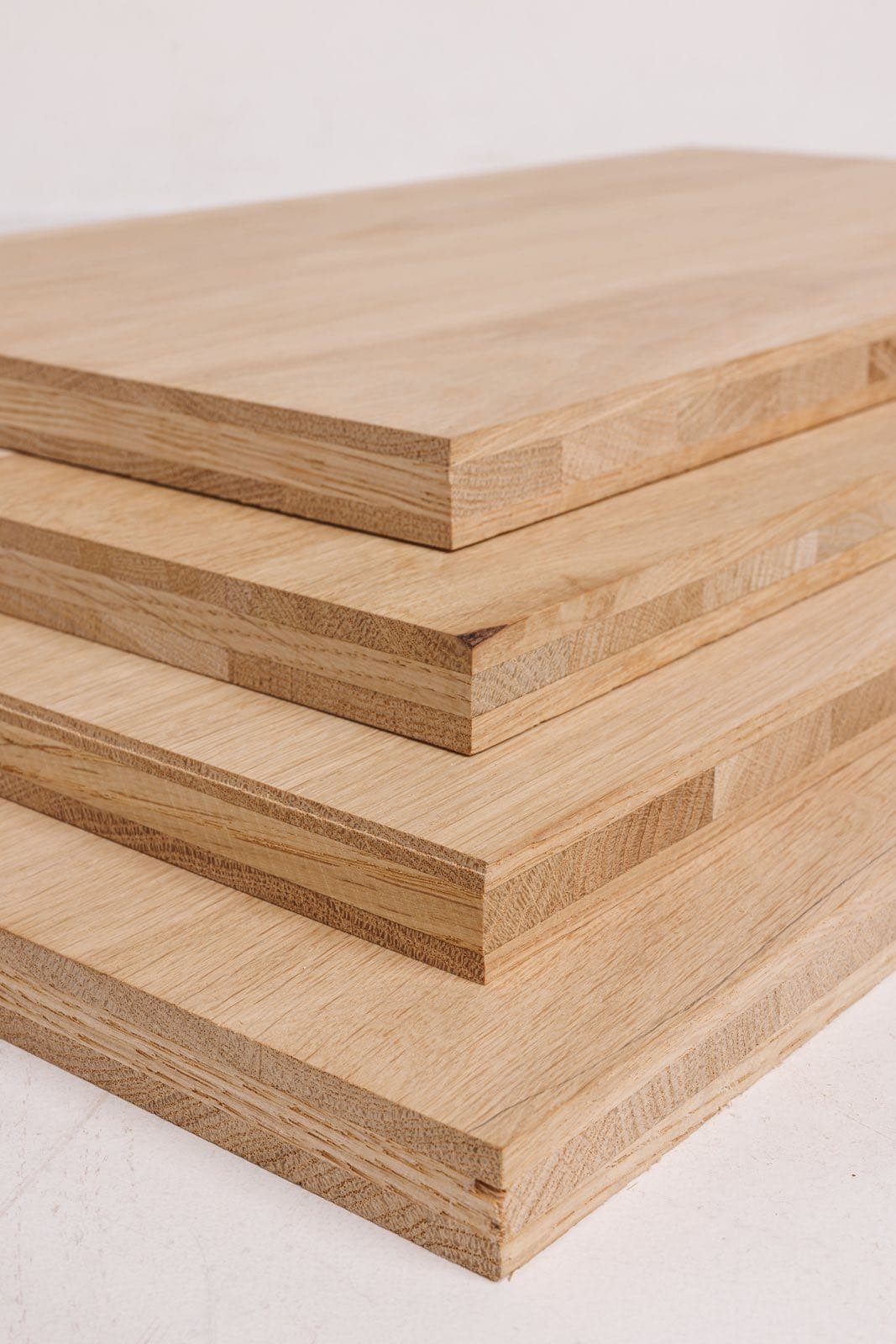 Stos jasnych, dębowych blatów drewnianych z widocznym przekrojem warstwowym, ułożonych jeden na drugim, prezentujących strukturę i wykończenie.
