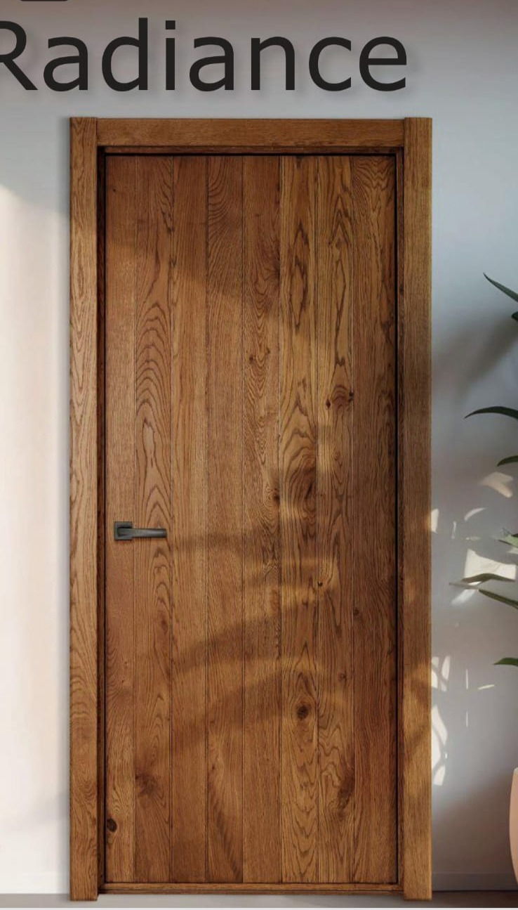 Drewniane drzwi wewnętrzne z pionowym usłojeniem,  ciemna klamka, minimalistyczna ościeżnica, w tle roślina doniczkowa i ściana w neutralnym odcieniu.