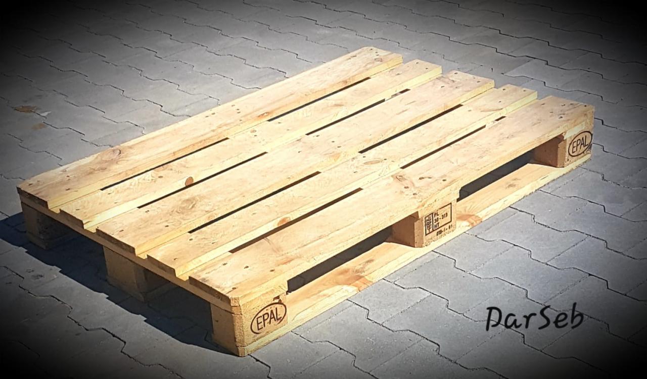 Jasna, drewniana paleta EPAL leżąca na szarej kostce brukowej w słoneczny dzień.