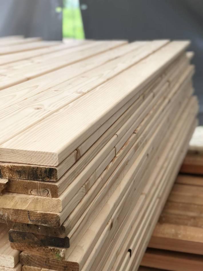 Stos jasnego, nowego drewna sosnowego, widoczne sęki i usłojenie, przygotowany do dalszej obróbki.