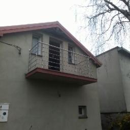 Unistal - Balkon z balustradą ze stali nierdzewnej w domu jednorodzinnym, widok z dołu, z drzewem w tle.