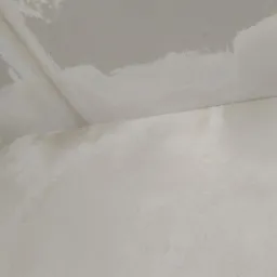 Ściana i sufit w trakcie prac przygotowawczych do malowania, z widocznymi śladami szpachlowania i nierównościami powierzchni.