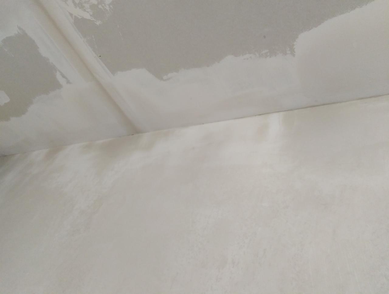 Ściana i sufit w trakcie prac przygotowawczych do malowania, z widocznymi śladami szpachlowania i nierównościami powierzchni.