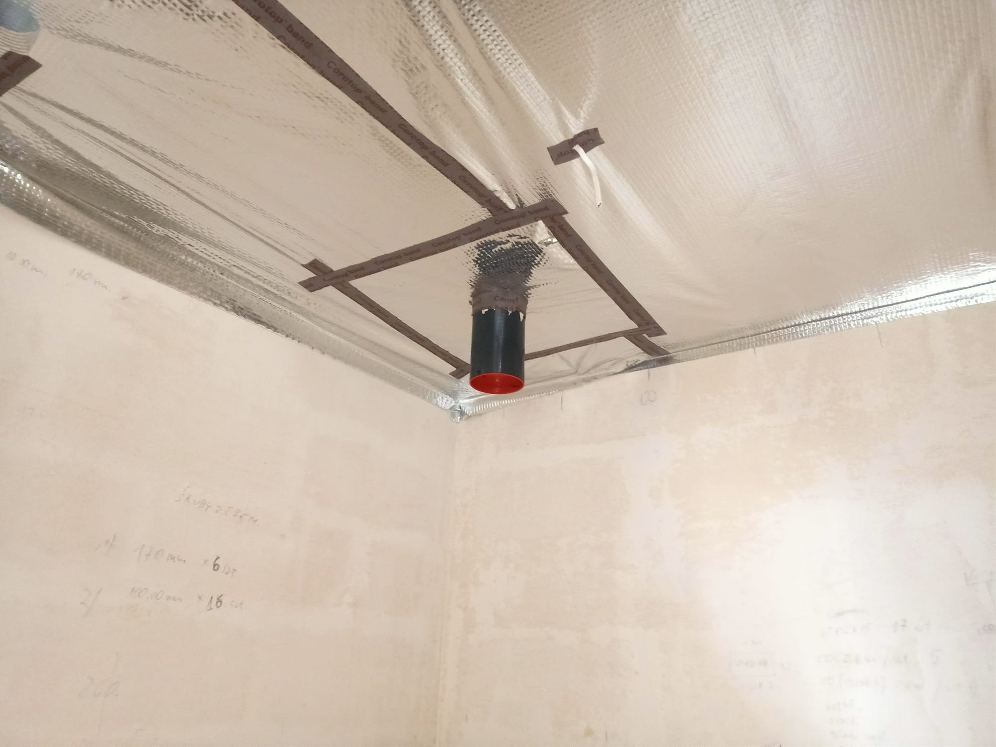 Montaż instalacji wentylacyjnej: widok na sufit z izolacją termiczną, z widocznym fragmentem kanału wentylacyjnego, mocowanego taśmą Corotop band