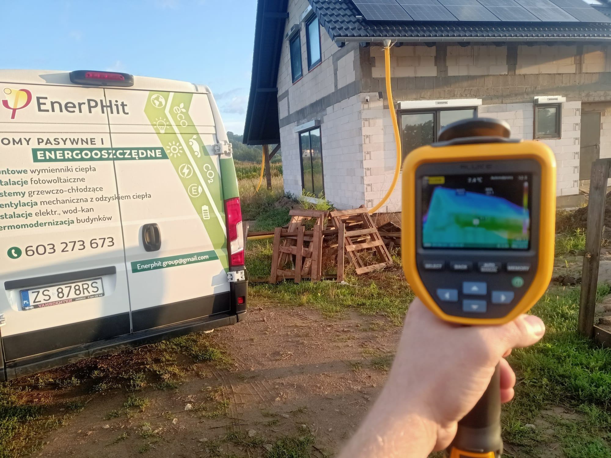 Termowizja budynku w trakcie budowy, widoczny samochód firmy EnerPhit i fragment instalacji fotowoltaicznej na dachu.