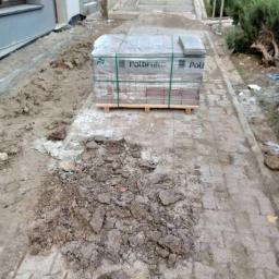 Błysk Paweł Szczepaniak - Paleta z kostką brukową Potbruk na chodniku, obok wykopana ziemia przygotowana pod ułożenie, widok z góry.