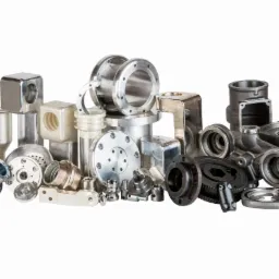 Zestaw precyzyjnie obrobionych metalowych komponentów o różnorodnych kształtach i wykończeniach, od polerowanych na wysoki połysk po surowe odlewy, ułożonych na białym tle.