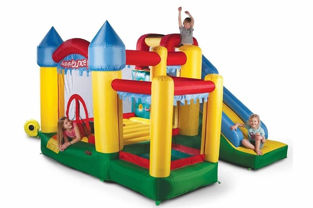 Kolorowy dmuchany zamek z tunelem i zjeżdżalnią, na którym bawią się dzieci.