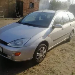 Srebrny Ford Focus kombi z widoczną tablicą rejestracyjną na tle budynku z czerwonej cegły i drabiny w Poznaniu.