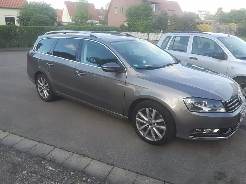 Szary samochód kombi marki Volkswagen Passat, zaparkowany na ulicy w dzielnicy mieszkalnej, z widocznymi felgami aluminiowymi i relingami dachowymi.