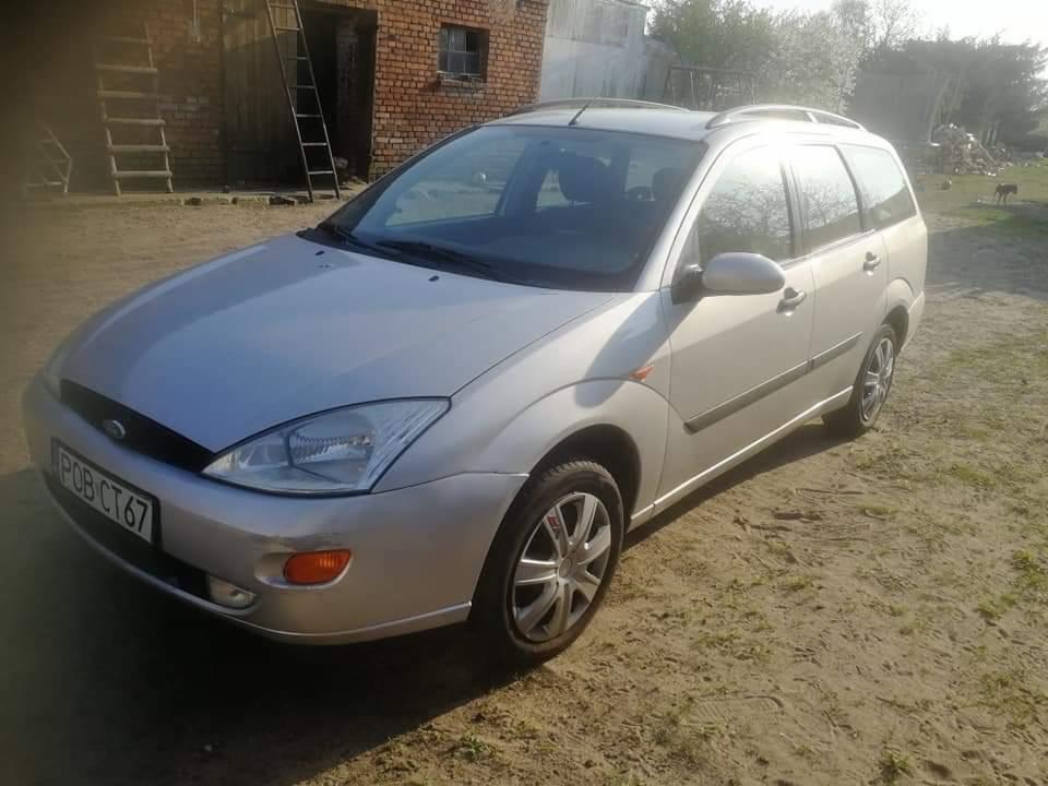 Srebrny Ford Focus kombi z widoczną tablicą rejestracyjną na tle budynku z czerwonej cegły i drabiny w Poznaniu.