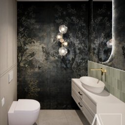 Nowoczesna łazienka z tapetą w motywy roślinne, wisząca toaleta, umywalka nablatowa i złota armatura. Oświetlenie punktowe i dekoracyjna lampa kulista.