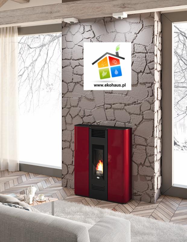 Czerwony piec na pellet z płomieniem w salonie, logo firmy na ścianie z kamienia, widok na zimowy krajobraz za oknem.
