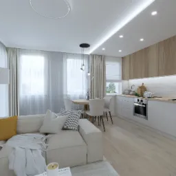 Jasne wnętrze mieszkania z aneksem kuchennym, okrągłym stołem jadalnym, sofą z poduszkami i pledem oraz drewnianą podłogą.