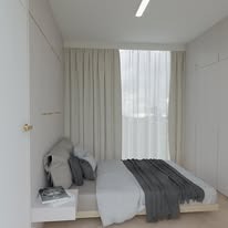Minimalistyczna sypialnia z łóżkiem na niskiej platformie, szare tekstylia, białe ściany i zasłony wpadające do pomieszczenia naturalne światło.