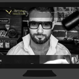 Czarno-białe zdjęcie monitora przedstawiającego stronę internetową salonu fryzjerskiego męskiego 'U Brzytwy', z wizerunkiem mężczyzny w okularach jako elementem graficznym strony.