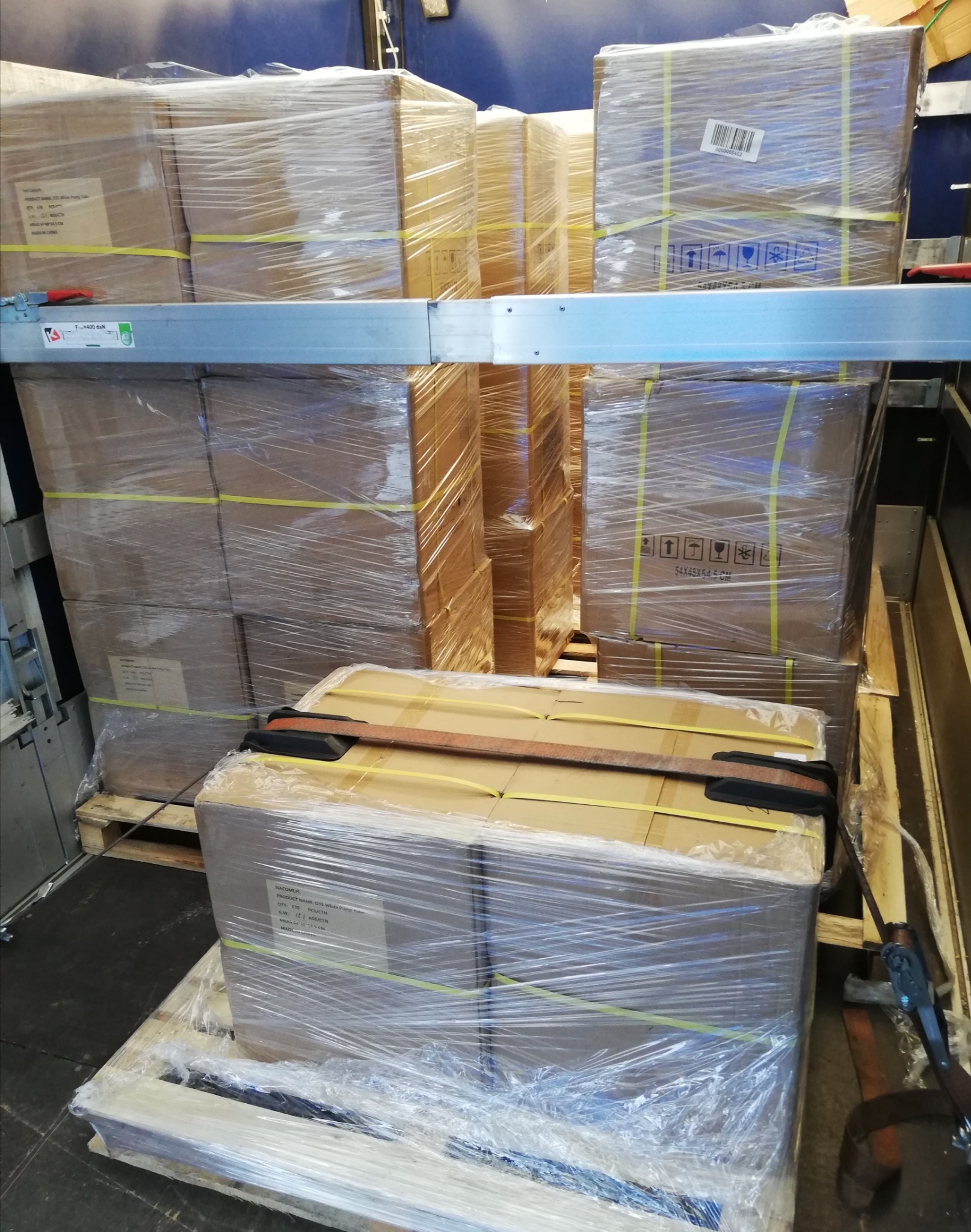 Wnętrze przestrzeni ładunkowej wypełnione kartonowymi pudłami na paletach, zabezpieczonymi folią stretch i pasami transportowymi.