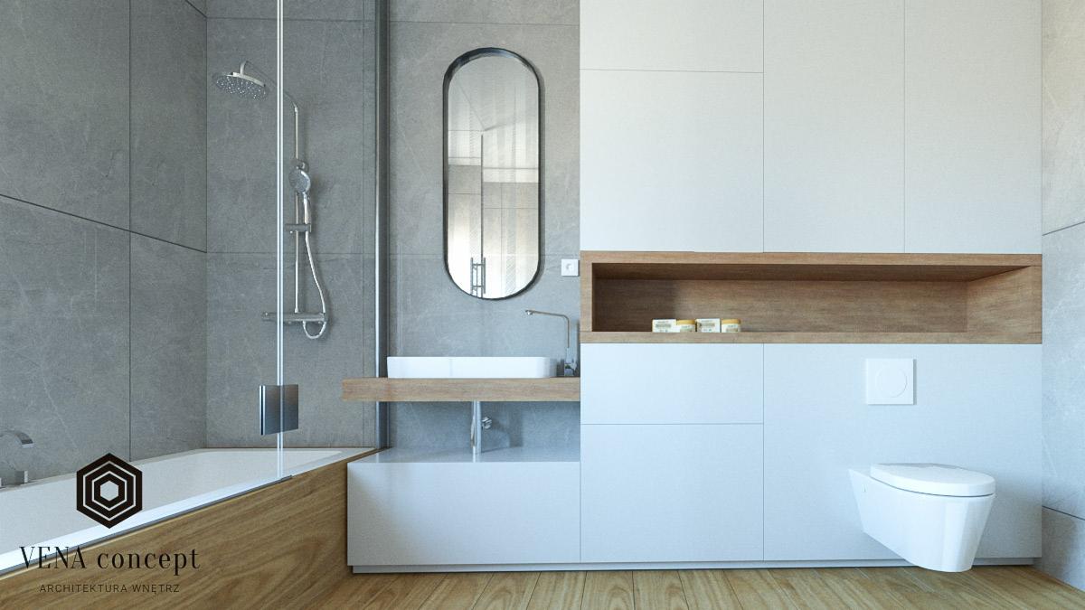 Nowoczesna łazienka z szarymi płytkami, białymi szafkami, drewnianymi akcentami i owalnym lustrem, widok na wannę z parawanem i toaletę podwieszaną.