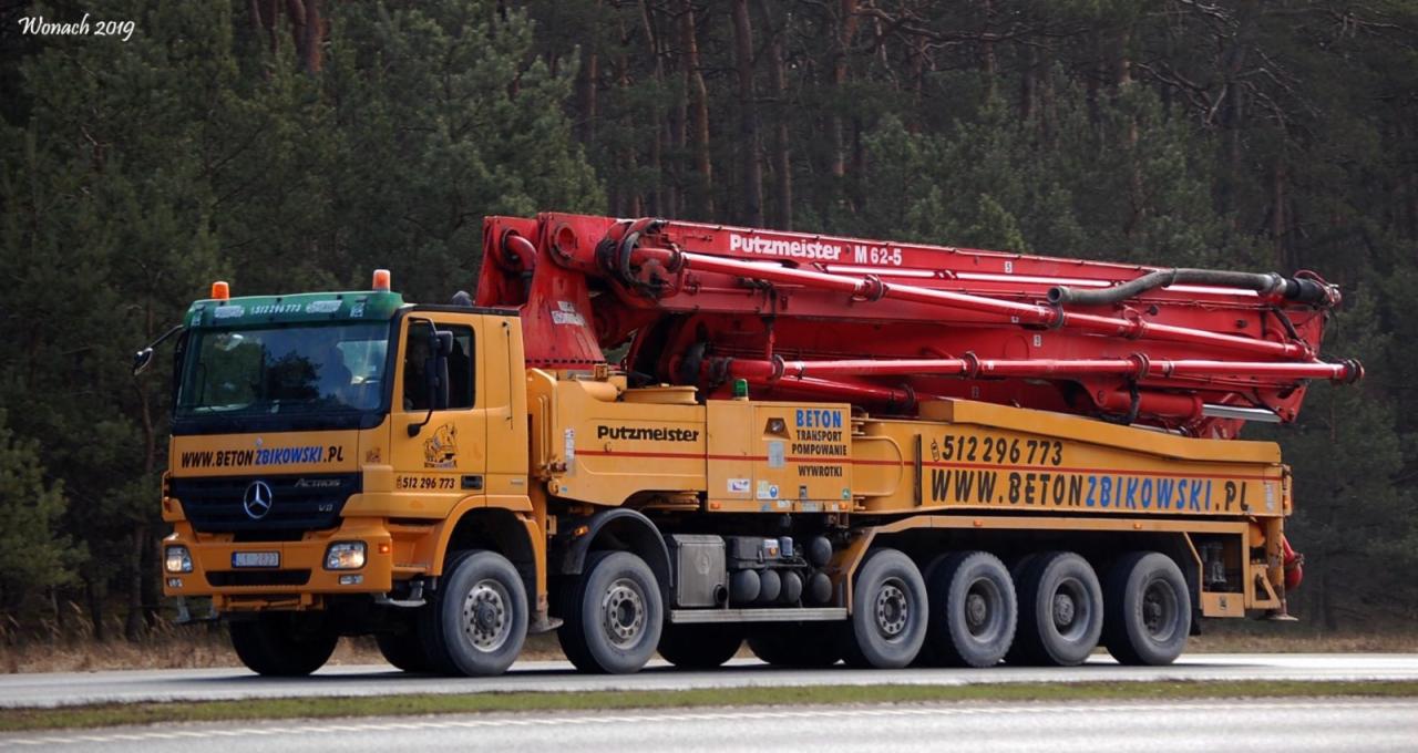 Żółta betonomieszarka Mercedes-Benz z czerwonym wysięgnikiem Putzmeister M 62-5 na tle lasu, z widocznym numerem telefonu i adresem strony internetowej firmy.