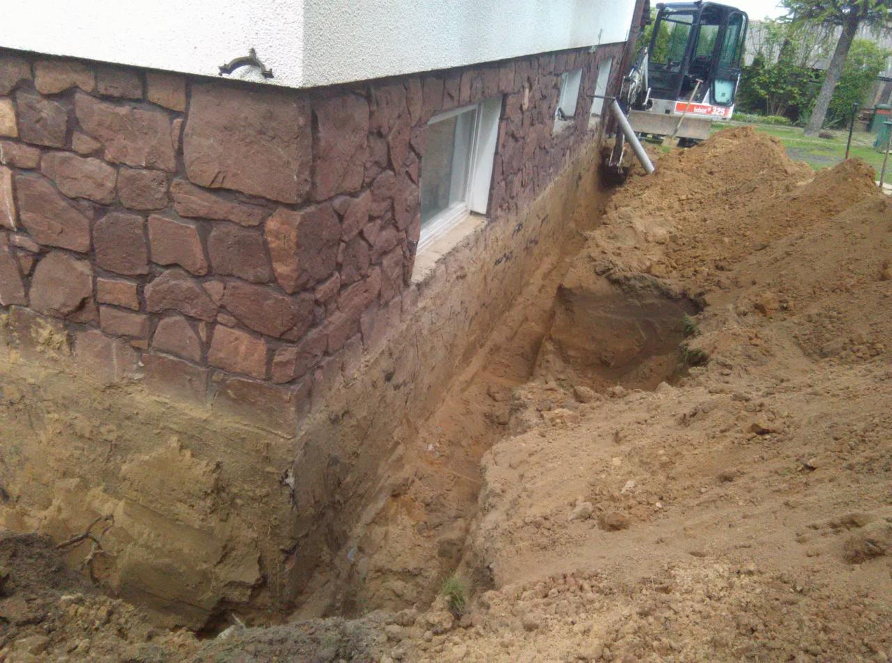 Wykop fundamentów pod budynek z elewacją z kamienia naturalnego, widoczna koparka Bobcat 325.
