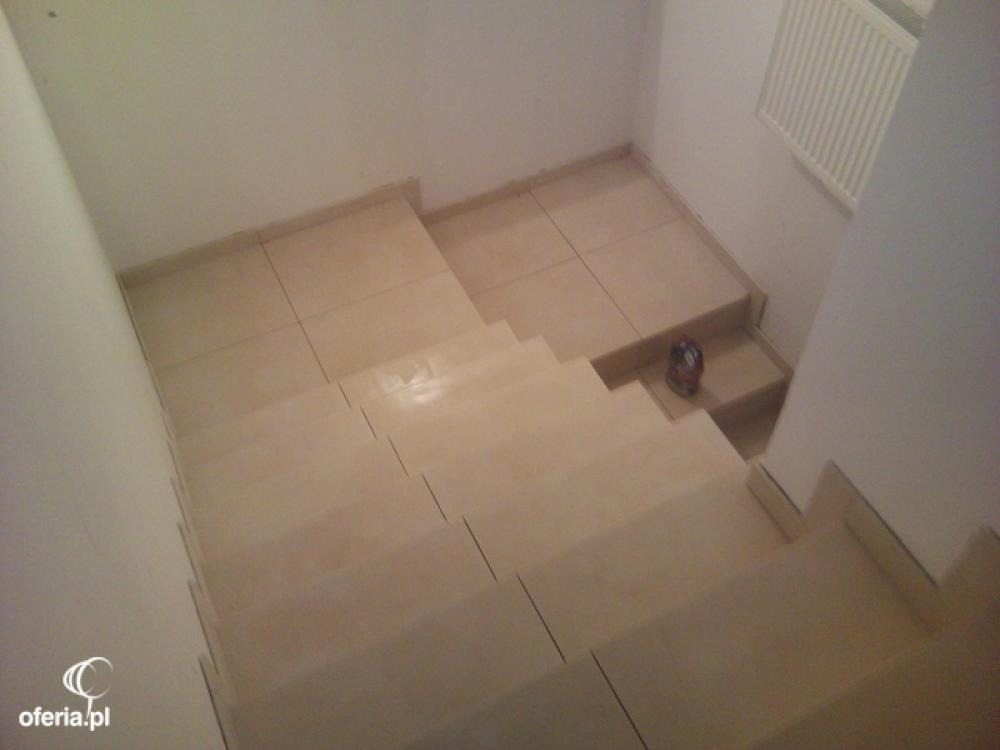 Schody wyłożone beżowymi płytkami ceramicznymi, widok z góry, na jednym ze stopni puszka po napoju.