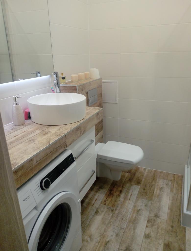 Nowoczesna łazienka z umywalką nablatową, pralką pod blatem imitującym drewno i płytkami podłogowymi w stylu rustykalnym.