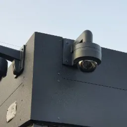 Dwie kamery IP kopułkowe zamontowane na rogu budynku w Bochni, widoczne przewody elektryczne na tle jasnego nieba.