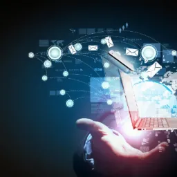 Ilustracja koncepcji integracji systemów IT w Międzyrzeczu: dłoń trzymająca laptopa, smartfona oraz wizualizacje połączeń sieciowych z mapą świata w tle.