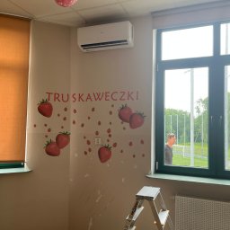 KRW SERWIS - Biała klimatyzacja na ścianie z naklejkami truskawek w pokoju z drabiną. Widok przez okno na zewnątrz. Dekoracja w stylu dziecięcym.