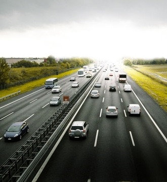 Autostrada z wieloma samochodami osobowymi i dostawczymi w ruchu, widok z góry, pochmurne niebo.