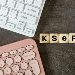 KSeF na drewnianych kostkach między białą i różową klawiaturą na ciemnym tle. Koncepcja Krajowego Systemu e-Faktur w księgowości.