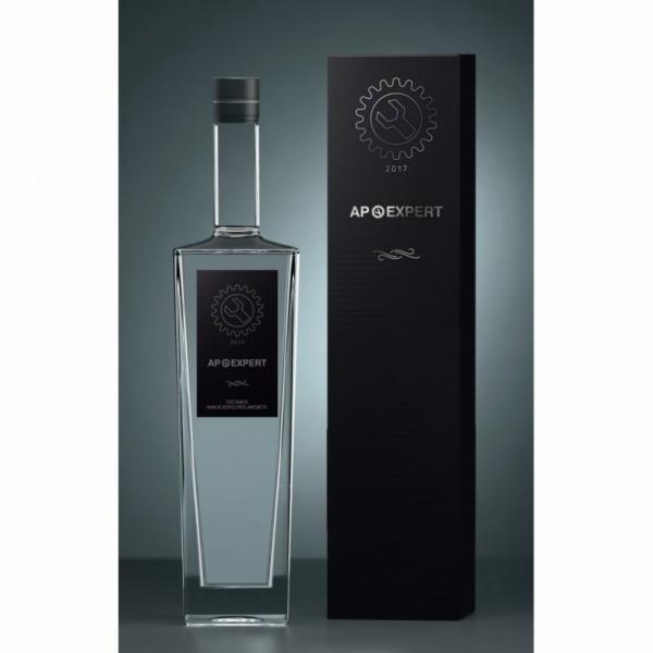 Elegancka, prostokątna butelka z przezroczystą zawartością i czarną etykietą z logo AP Expert, obok czarne pudełko z identycznym logo, na szaro-czarnym tle.