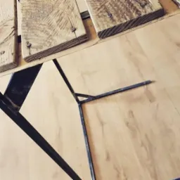 Surowy blat z desek z odzysku, mocowany śrubami do metalowej, spawanej konstrukcji nóg, na tle drewnopodobnej podłogi.