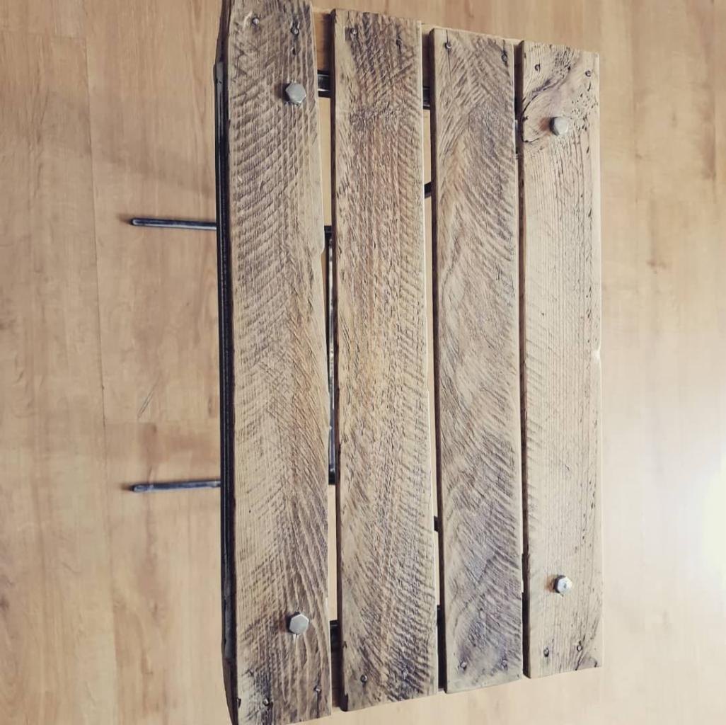 Panel z postarzanych desek drewnianych, połączonych metalowymi elementami, widoczne ślady po gwoździach i naturalne usłojenie drewna.
