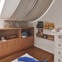 Madde studio Sp. z o.o. - Pokój dziecięcy na poddaszu: drewniane meble, półki z książkami, pluszowy wieloryb na dywanie i baldachim nad łóżkiem. Przytulne i funkcjonalne wnętrze.