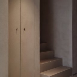Madde studio Sp. z o.o. - Minimalistyczne wnętrze: zabudowa szafy w odcieniach beżu i schody w tonacji ziemi. Nowoczesny design, stonowana kolorystyka, gładkie powierzchnie.