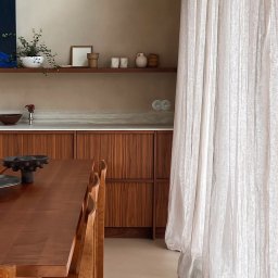 Madde studio Sp. z o.o. - Jadalnia w stylu minimalistycznym: drewniany stół i krzesła, zabudowa kuchenna z drewna, półka z dekoracjami, zwiewne zasłony w naturalnych odcieniach.