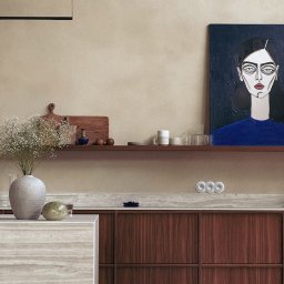 Madde studio Sp. z o.o. - Minimalistyczna kuchnia: drewniane szafki, marmurowy blat, półka z dekoracjami i obraz z portretem kobiety w niebieskiej bluzce. Stonowana kolorystyka.