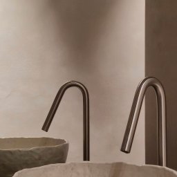Madde studio Sp. z o.o. - Minimalistyczna łazienka: Dwie ceramiczne umywalki z nowoczesnymi, metalowymi kranami na tle ściany w odcieniach beżu. Subtelne oświetlenie.