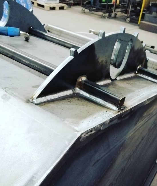 Metalowa konstrukcja spawana z elementami zębatymi, widoczne spawy i elementy mocujące z rur.