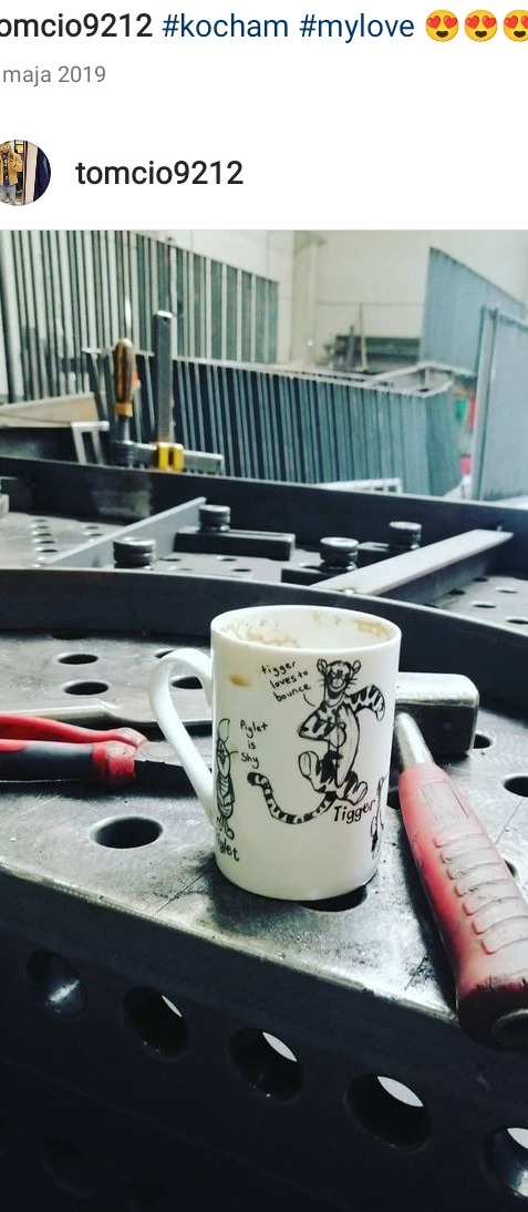 Mug with Tigger cartoon on a perforated metal welding table, with pliers and a welding tool nearby, suggesting a break during metalwork.